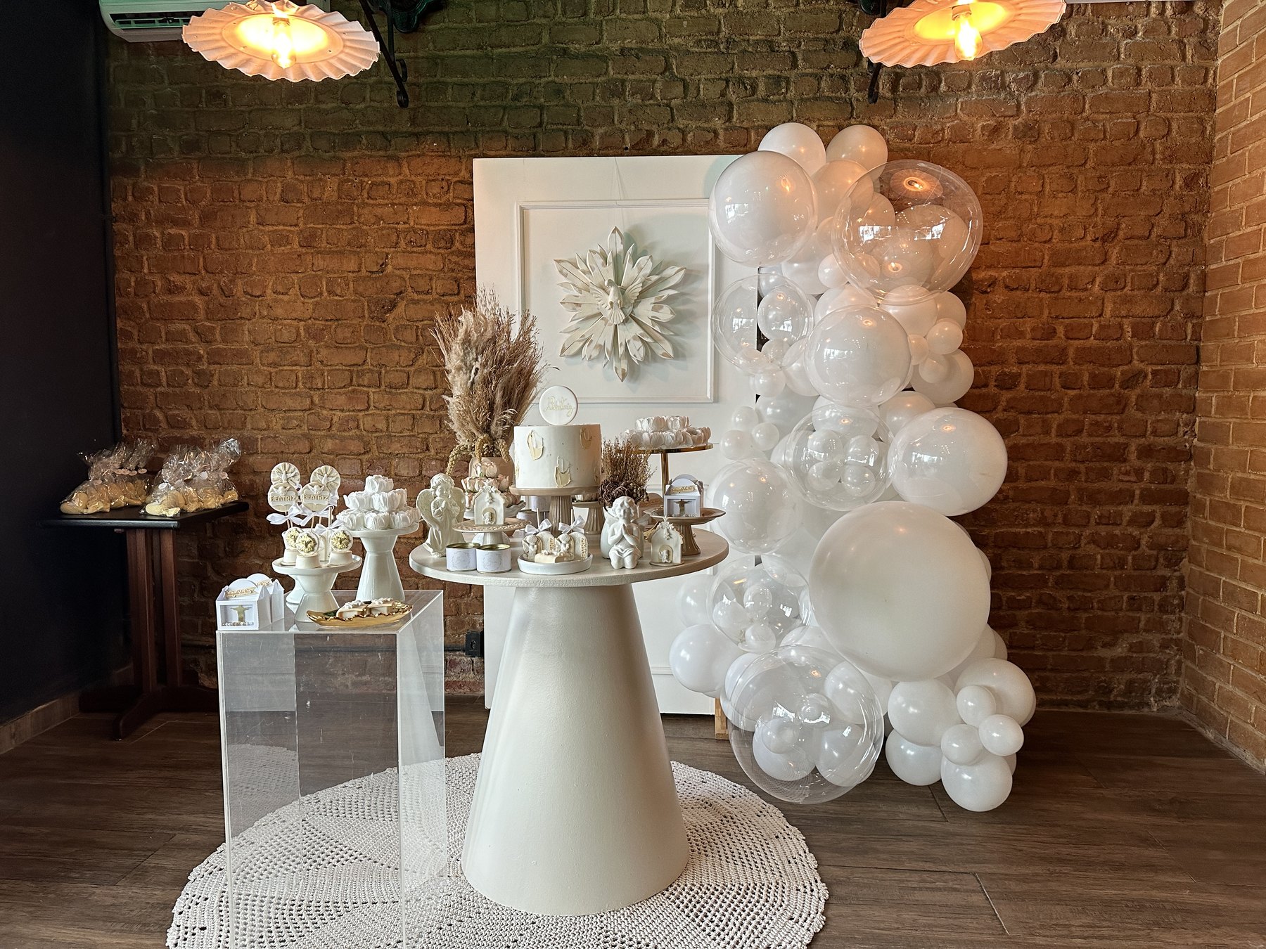 Decoração de celebração no Vitral, com arranjo branco e arco de balões.